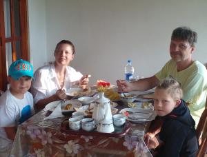 a family sitting at a table eating food at Racy Nature Cottage in Ella