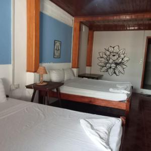 a room with two beds and a table with a lamp at Nomad Guesthouse in Kratie
