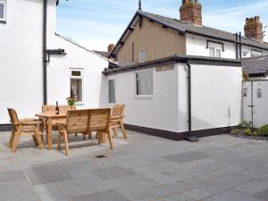 a patio with a wooden table and chairs in front of a house at Mulberry House in Lytham St Annes