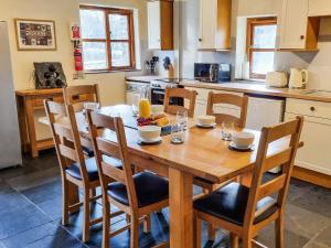 a kitchen with a wooden table with chairs and a tableasteryasteryasteryasteryastery at Ty Nicw - W42765 in Blaenpenal