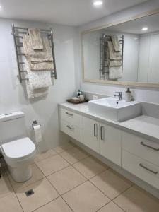a bathroom with a toilet and a sink and a mirror at Ocean view apartment! 300m to beach. Pet friendly. in Alexandra Headland