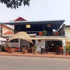 a building with a patio with tables and chairs at Nomad Guesthouse in Kratie