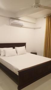 1 dormitorio con 1 cama grande con sábanas blancas en Rodrigo Apartments en Boralesgamuwa