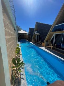 a swimming pool next to a house with blue water at Villa completa confotable para 9 personas in Pedernales