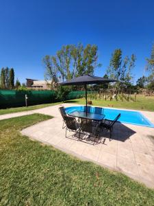a table and chairs with an umbrella next to a pool at Saint Rose Espacio Organico en Viñedo con Piscina en Lujan de Cuyo in Mendoza