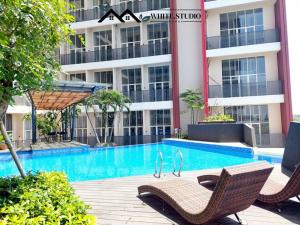 a swimming pool with two chairs and a building at White Studio Group Surabaya - WS 821 at Amega Crown Residence in Tambakoso