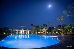 una piscina por la noche con la luna en el cielo en Samanea Beach Resort & Spa en Kep