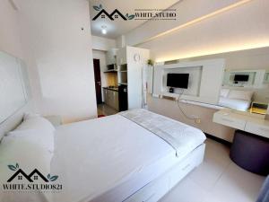 a bedroom with a white bed and a television at White Studio Group Surabaya - WS 821 at Amega Crown Residence in Tambakoso