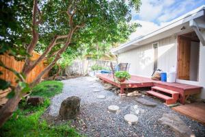 un patio trasero con un banco de madera y un árbol en Cute Guest Suite in Kailua with AC!!! en Kailua