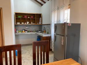 cocina con nevera, mesa y sillas en Oceano Beach Villa en Arugam Bay