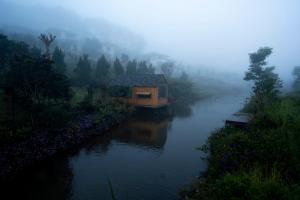 a small house on a river in the fog at Ngôi Làng Trong Tranh, Leading-Kiwuki Village in Bao Loc