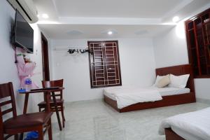a bedroom with two beds and a table and chairs at Thinh Khang Guesthouse in Buon Ma Thuot