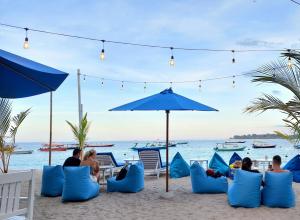 a group of people sitting on the beach under an umbrella at Cosè Gili Beach Resort in Gili Trawangan