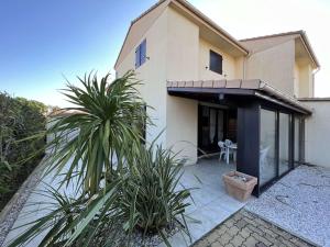 a house with glass doors and plants in front of it at Maison Vendres, 5 pièces, 10 personnes - FR-1-701-15 in Vendres