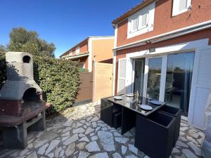 a patio with a table and an outdoor oven at Maison Vendres, 2 pièces, 4 personnes - FR-1-701-41 in Vendres