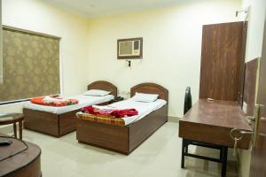 a room with two beds and a table and a desk at Hotel Komala Vilas in Kolkata