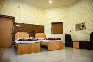 two beds in a room with a couch and chairs at Hotel Komala Vilas in Kolkata