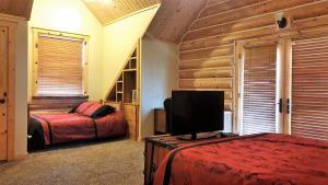 a bedroom with two beds and a flat screen tv at Teton Hostel HideAway in Driggs