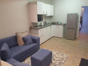 a living room with a blue couch and a kitchen at Northlands Manor in Durban