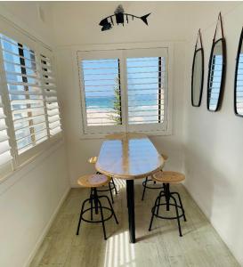 uma mesa e dois bancos numa sala com pranchas de surf em The Fisherman's Shack em The Entrance