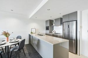 a white kitchen with a table and a refrigerator at Avalon Apartments - Wow Stay in Gold Coast