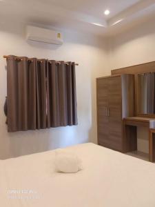Mac's Bay Resort في بان تاي: غرفة نوم بسرير وستارة بنية اللون
