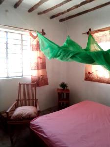 1 dormitorio con cama, silla y bandera verde en Bibi Mrembo Guesthouse, en Pingwe