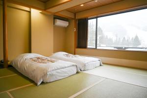 2 Betten in einem Zimmer mit einem großen Fenster in der Unterkunft Hotel Goryukan in Hakuba