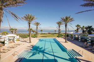 uma piscina com palmeiras e o oceano em SouthernVilla Ticket to Paradise em Palm Coast
