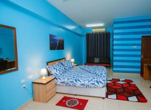 1 dormitorio con paredes azules, 1 cama y 1 mesa en Queens Rentals - Studio Apartments - Village Walkway - Masaki - Dar es Salaam en Dar es Salaam