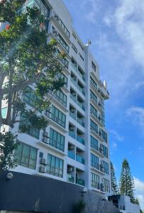 un edificio blanco alto con un árbol delante de él en One Tagaytay Place Hotel Suites OFFICIAL ACCOUNT, en Tagaytay