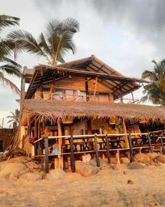 een huis met een rieten dak en een palmboom bij Indika Beach Villa in Galle
