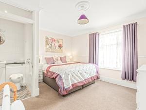 a white bedroom with a bed and a window at Cosy Cottage in Lyndhurst