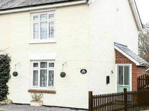 a white house with a fence in front of it at Cosy Cottage in Lyndhurst