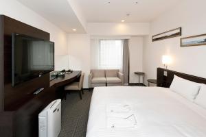 a hotel room with a bed and a desk and a television at Sotetsu Fresa Inn Yokohama Sakuragi-cho in Yokohama