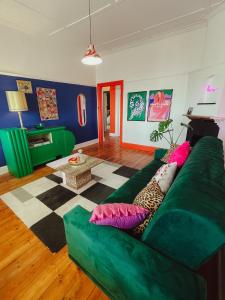 una sala de estar con un sofá verde con almohadas coloridas en HARBOUR VIEW FUNKY AND ECLECTIC TWO BEDROOM HOME en Mossel Bay