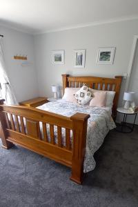 a bedroom with a wooden bed with two pillows at Kaimai Sunset Bed & Breakfast in Matamata
