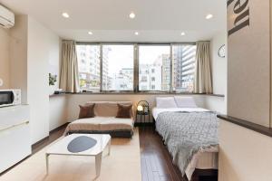 um quarto de hotel com duas camas e um sofá em ZEROSHARE CHIKKO em Osaka