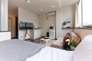 1 dormitorio con cama, sofá y TV en ZEROSHARE CHIKKO en Osaka