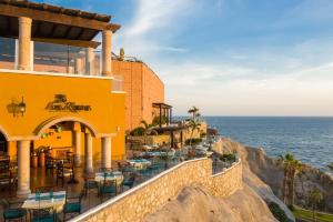 a restaurant on the side of a cliff next to the ocean at Villas At Hacienda Encantada in Cabo San Lucas
