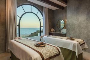 two beds in a room with a view of the ocean at Villas At Hacienda Encantada in Cabo San Lucas