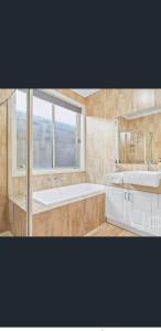 een badkamer met 2 wastafels, een bad en een raam bij Private Room3 20 min CBD CITY Airport in Truganina