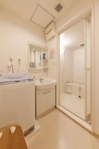a white bathroom with a sink and a shower at ZEROSHARE CHIKKO in Osaka