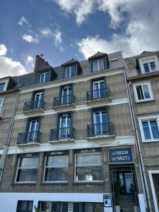 サン・バレリ・アン・コーにあるLa Maison Des Galets sur le front de merの大きなレンガ造りの建物で、窓とバルコニーが付いています。