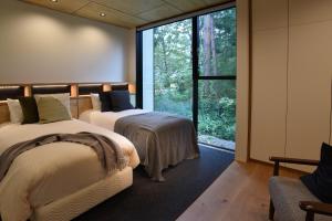 two beds in a room with a large window at Prominence by The Hakuba Collection in Hakuba