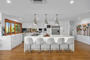 a kitchen with a large white island with bar stools at Broadbeach Bungalow - Heated Pool - Sleeps 7 in Gold Coast