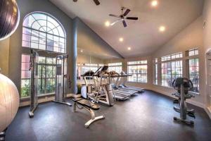 a gym with treadmills and ellipticals in a room with windows at LuxCation At Med Center Free Parking & WIFI in Houston