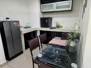 uma pequena cozinha com uma mesa de vidro e um frigorífico em The Viana Apartment IV em Kota Bharu