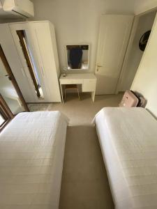 two beds in a room with a desk and a mirror at Aristotelis Apartment in Nikiti
