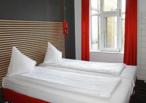Cama con sábanas blancas y almohadas junto a una ventana en Annex Copenhagen, en Copenhague